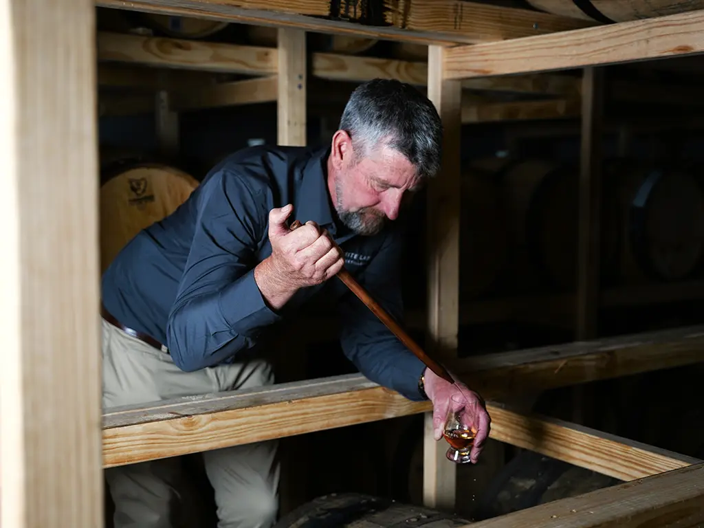 anthony white, head distiller at the white label distillery testing matured whisky in the warehouse